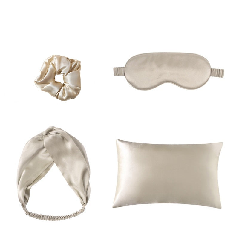 Set of satin sleep accessories including a headband, eye mask, and pillow on a white background.